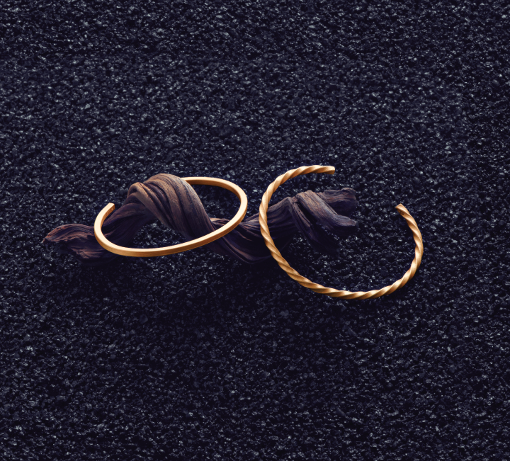 Gold bracelets styled on dark textured surface